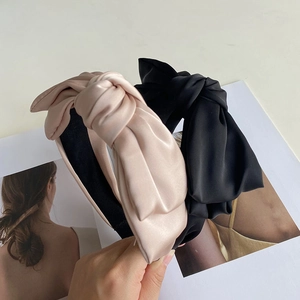 Macro shot of satin bow headbands in beige and black with a smooth silky texture