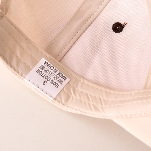 Macro shot of 100% cotton kids baseball cap interior showing stitching and labels