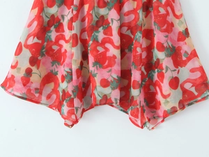 Dettaglio dell'orlo della gonna in chiffon con stampa di fragole e ciliegie e taglio a punta