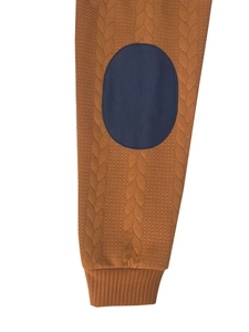 Dettaglio manica in maglia caramello con toppa blu navy e trama a trecce