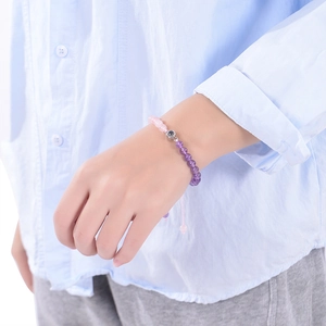Pink and purple beaded projection bracelet with a silver charm shown on a woman wrist