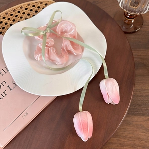 Close-up of pink tulip hair scrunchie with green ribbons and hanging flower buds