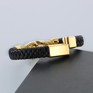 Detailed view of black braided leather bracelet with golden hook clasp on display
