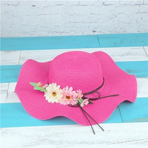 Detailed view of rose pink straw hat with artificial daisy flowers and brown string