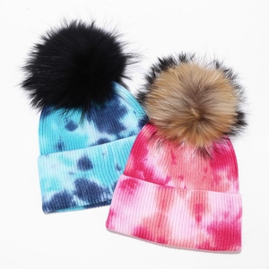Women's tie-dye knit beanie hats with large fluffy faux fur pom poms in colorful styles