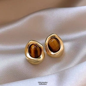 Detail of vintage gold plated oval earrings with brown cat-eye stones on silk fabric