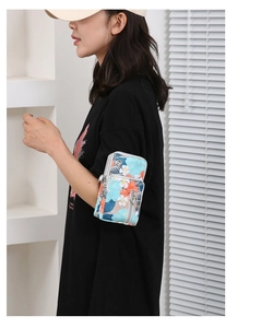 Detail of tropical floral crossbody phone bag with dual zippers and heart-shaped pulls