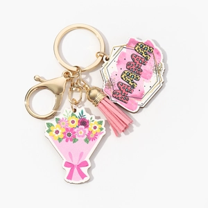Detailed view of the MOM keychain with pink tassel and floral charm on a gold metal ring