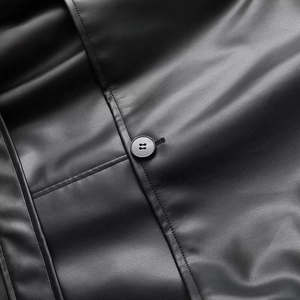 Close-up of premium black leather trench coat showing fine texture and button detail