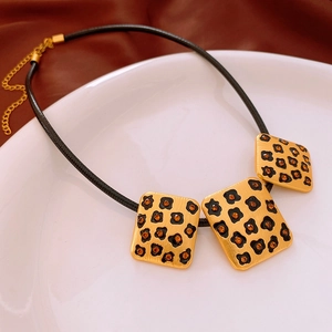 Détail de pendentifs vintage léopard dorés avec cristaux orange sur un cordon noir