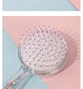 Detail of round hairbrush with clear handle filled with colorful sequins and purple bristles