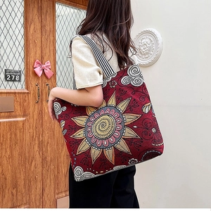 Detail of red bohemian jacquard tote bag with mandala pattern and striped shoulder strap