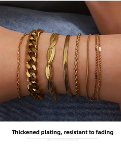 Close-up of golden stainless steel snake and cuban link bracelet set on denim background