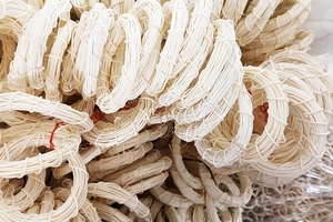 Macro shot of hand-woven cream Indonesian rattan rings showing detailed natural textures