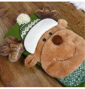 Close-up of green knitted Christmas stocking featuring a plush reindeer on wood floor