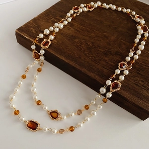 Detail of vintage multi-layer pearl necklace with amber faceted gems and gold chain
