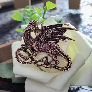 Vintage bronze dragon brooch with purple rhinestones on a white rose