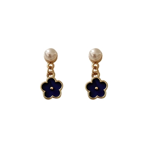 Elegant gold earrings with white pearl and navy blue flower pendants on white background