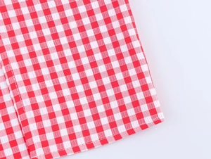 Makroaufnahme von rot-weißem Gingham-Stoff mit hochwertiger Kantenverarbeitung am Kleid
