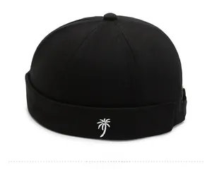 Detail shot of black docker hat featuring white coconut tree embroidery on the cuff