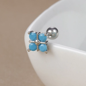 Detailed macro view of retro cross earrings with turquoise blue stones on a ceramic bowl