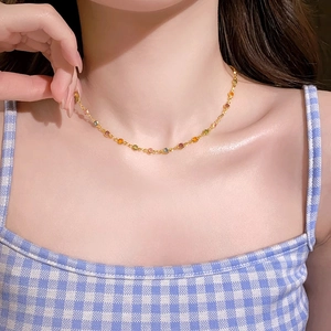 Detailaufnahme einer goldenen Halskette mit bunten Zirkon-Blumen am Hals eines Models