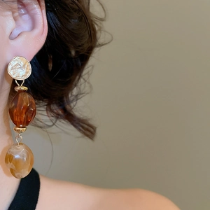 Close-up of retro layered acrylic beaded earrings with amber and marble resin on model
