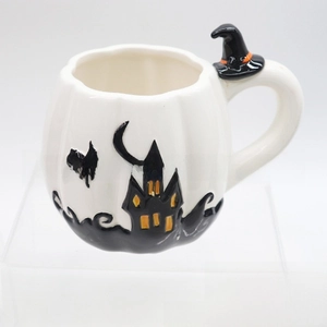 Detail of white pumpkin ceramic mug with black embossed castle and witch hat handle