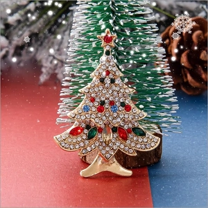 Golden Christmas tree brooch with colorful rhinestones on festive pine background