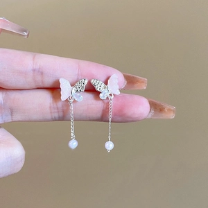 Détail de boucles d'oreilles papillon roses avec cristaux et longues chaînes à glands