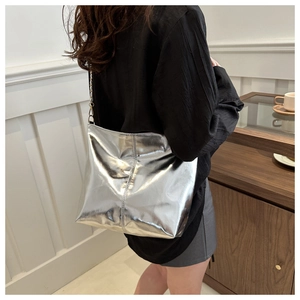 Silver metallic bucket bag with chain strap and pleated finish shown on shoulder