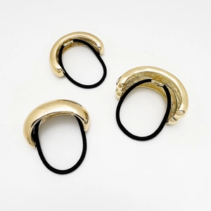 Detailed view of three polished gold U-shaped metal hair ties with black elastic bands