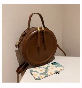 Detailansicht einer runden Vintage-Umhängetasche mit Gänseblümchen-Handyhülle zum Vergleich
