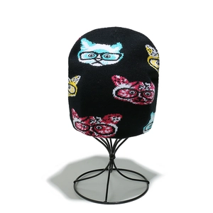 Detailed knit texture of black beanie featuring colorful cartoon cats with glasses