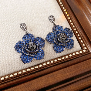 Detailed view of vintage blue flower earrings with zircon stones on beige fabric