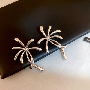 Macro shot of silver palm tree earrings with high-polish finish on leather surface