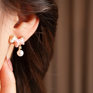 Close-up of pink enamel puppy earring with 18K gold plating and a pearl drop on model