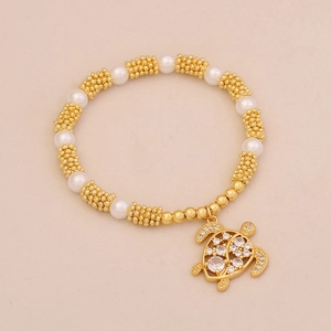 Detail of gold beaded bracelet featuring a turtle pendant with crystal rhinestones