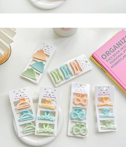 Flat lay of macaron-colored hair claw clips set in pastel pink and green on white cards