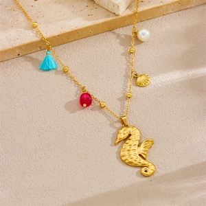 Detail of gold seahorse necklace featuring blue tassel, red beads and shell pendants