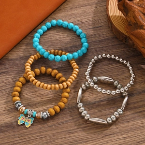 Detail view of Bohemian turquoise and wood bead bracelets with butterfly charm on a wooden surface