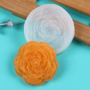 Macro shot of 3D peony silicone mold with detailed orange resin flower on blue surface