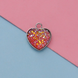 Macro view of a 13mm silver heart-shaped pendant with red glitter resin filling and jump ring