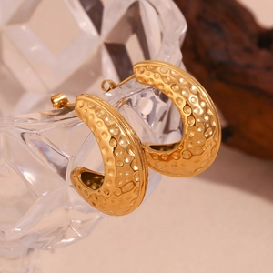 Détail macro de boucles d'oreilles coque d'arachide dorées 18K à texture martelée
