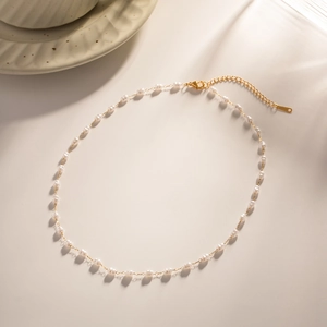 Detail of gold chain necklace with irregular white pearls and secure lobster clasp closure