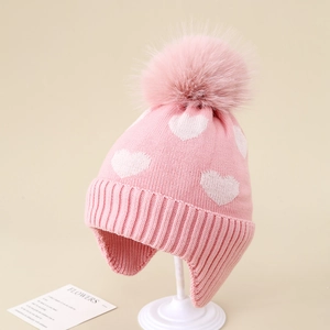 Detailed knit texture and soft faux fur pom-pom on pink heart pattern earflap hat