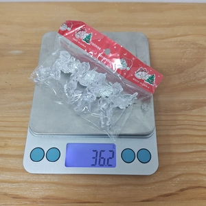 Detailed view of clear acrylic angel ornaments being weighed on an electronic scale