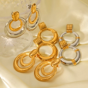 Modern two-tone stainless steel hoop earrings on elegant silk and glass display stand
