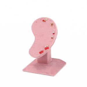 Close-up of red and gold cherry and strawberry stud earrings on a pink velvet display