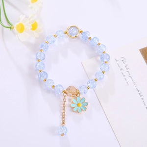 Close-up of blue crystal flower bracelet with golden beads on a minimalist white table
